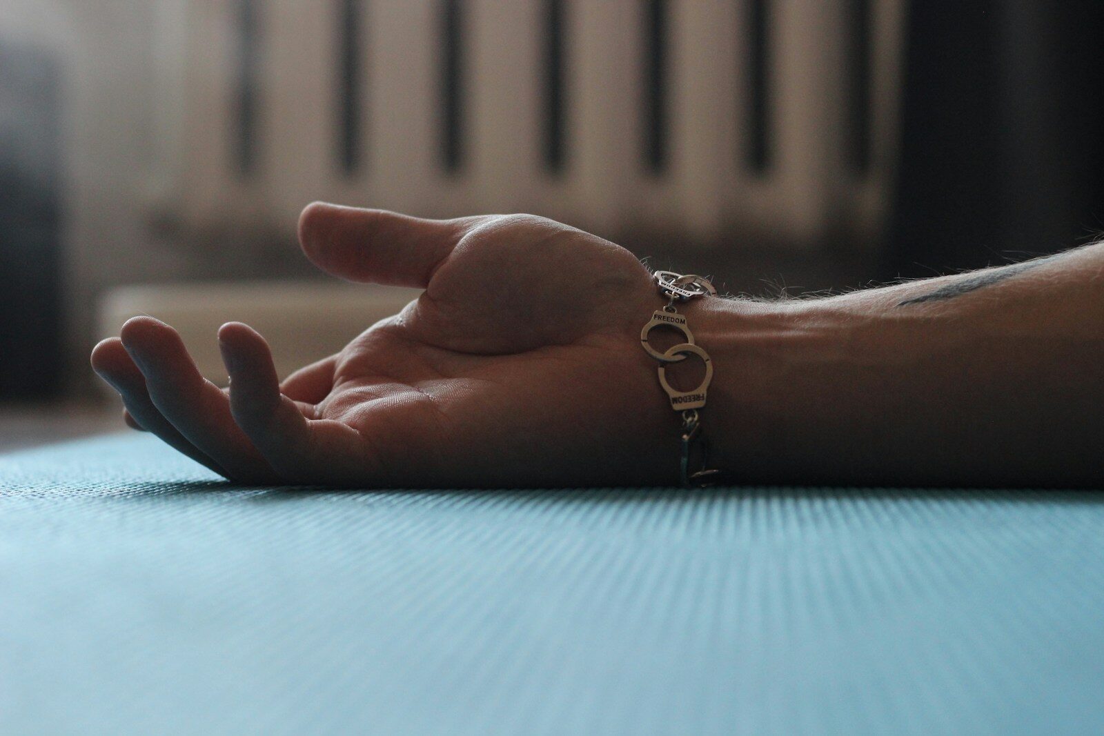 A person's hand resting on a table with a radiator in the